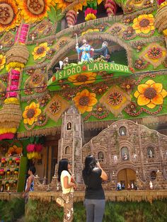 two women standing in front of a building decorated with flowers