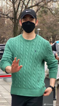 a man wearing a black face mask and green sweater