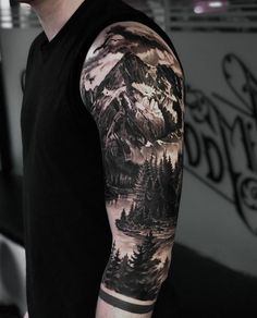 a man's arm covered in black and grey ink with mountains, trees and water