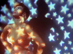 a woman standing in front of a screen with stars all over her body and chest