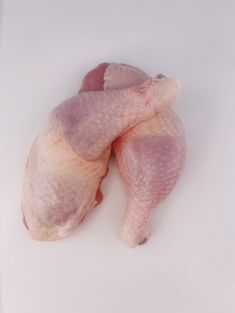 two pieces of raw chicken sitting next to each other on a white counter top,