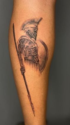 a tattoo on the leg of a man with a helmet and spear in his hand