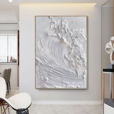 a large white painting hanging on the side of a wall next to a dining room table