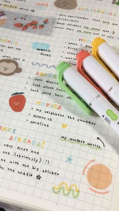 three pens sitting on top of a notebook with some stickers next to each other