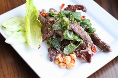 a white plate topped with meat and veggies on top of a wooden table