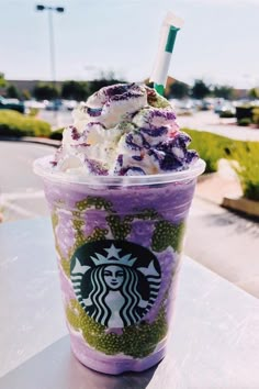 a purple starbucks drink with whipped cream and sprinkles on the top, sitting on a table outside