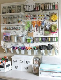 organized craft room with pegboard, scissors and other items on the wall behind it