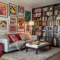 a living room filled with lots of books and pictures on the wall next to a couch