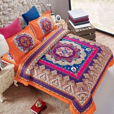 a bed with an orange comforter and colorful pillows