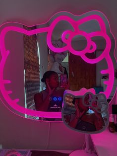 a person taking a photo in a mirror with a pink hello kitty light up vanity mirror