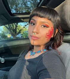 a woman with red painted on her face sitting in a car