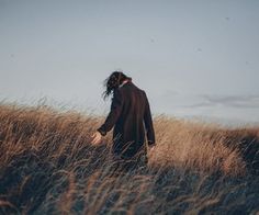 a person walking through tall grass on a sunny day