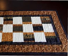 a close up of a quilted place mat on a wooden table with black and white squares