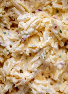 a close up view of macaroni salad with cheese and herbs on it's side