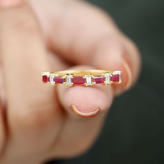 a person holding a gold ring with three stones on the outside and one stone in the middle