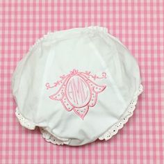 a pink and white checkered table cloth with a monogrammed diaper on it