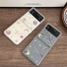 two phone cases sitting next to each other on top of a wooden table with plates and utensils