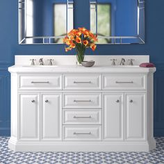 a bathroom vanity with two mirrors above it and flowers in the bowl on the counter