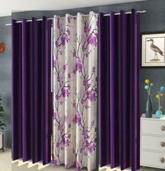 a living room with purple and white curtains in front of a window that has flowers on it