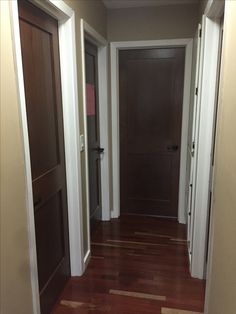 an empty hallway with wooden floors and two doors leading to another room in the house