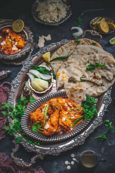 an assortment of food on a silver platter with other dishes and utensils