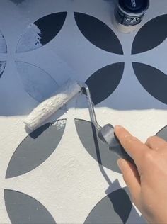 someone using a brush to paint a wall with white and black circles on the floor