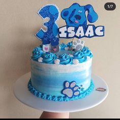 a birthday cake with blue frosting and an animal themed number 3 on top is shown