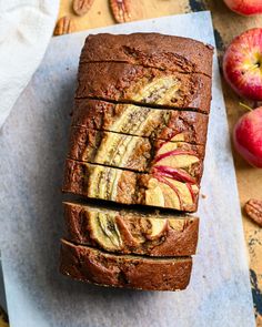 sliced loaf of banana bread sitting on top of a cutting board next to an apple