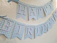 a blue and white happy birthday banner with gingham paper on the bottom, hanging from a wall