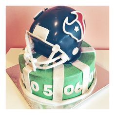 a football helmet on top of a green and white cake that is shaped like a gift box