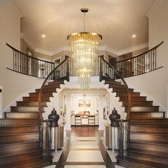 an elegant foyer with chandelier and wooden stairs