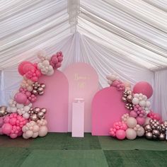 a pink and white balloon arch with balloons