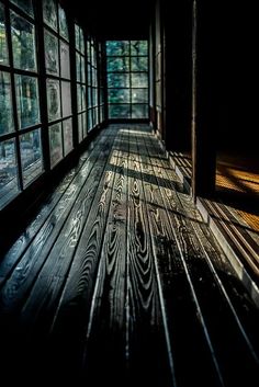 an empty room with lots of windows and wood flooring on the side of it