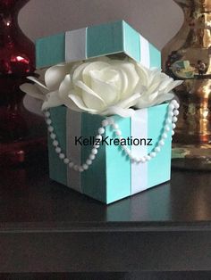 a blue box with pearls and a white rose in it