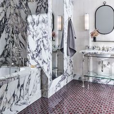 a bathroom with marble walls and red tile flooring, two sinks and a bathtub