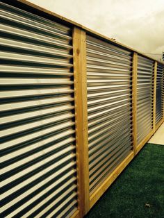 a fence made out of metal and wood with grass in the foreground next to it