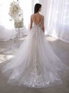 a woman in a wedding dress looking back at the camera while standing next to a birdcage