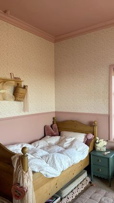 a bedroom with pink walls and a bed in the corner next to a small table