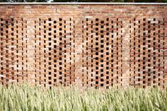 a brick wall with grass growing in front of it