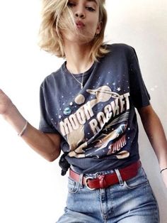 a woman with blonde hair blowing bubbles in her mouth while wearing a t - shirt that says moon flight