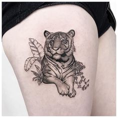 a black and white tiger tattoo on the back of a woman's thigh,