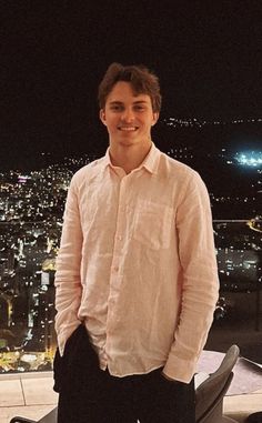 a young man standing in front of a city at night