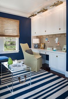 a living room with blue walls and white furniture in the center, along with a striped rug on the floor