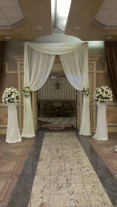 the entrance to an elegant wedding venue with white flowers and drapes on either side