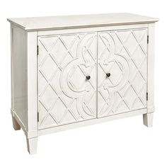 a white cabinet with two doors and an ornate design on the front, against a white background