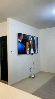 a flat screen tv mounted to the side of a wall in an empty living room