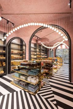 the inside of a bakery with lots of shelves and lights hanging from it's ceiling