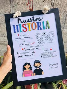 a person holding up a framed poster with the words musta history written in spanish