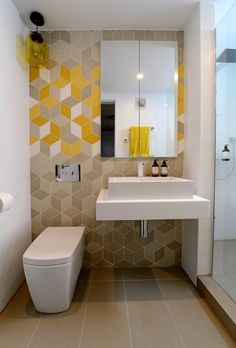 a white sink sitting under a bathroom mirror next to a yellow towel hanging on the wall