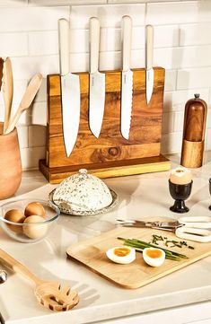 an assortment of kitchen utensils on a counter top with eggs and other ingredients